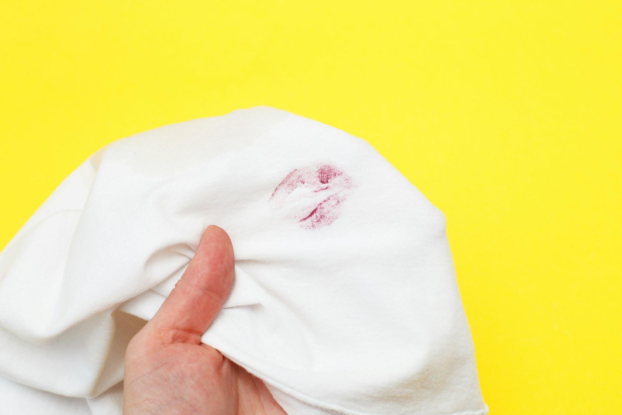 Woman holding a white shirt with red kiss lipstick on a yellow background